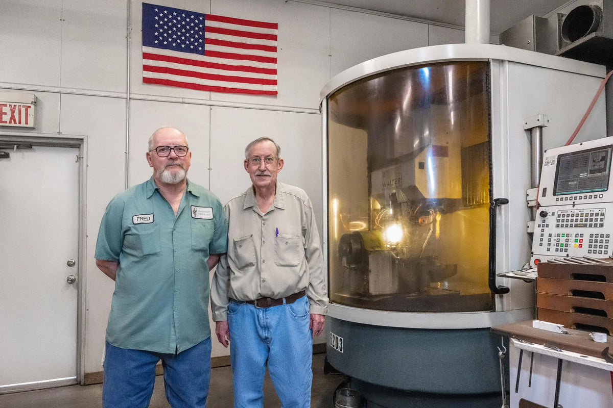Workers standing beside industrial CNC machine